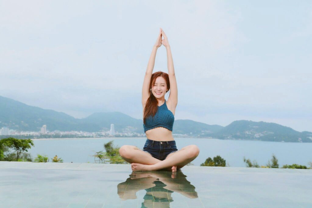 Young woman doing yoga by a scenic waterfront, enjoying a serene landscape, article Can I Do a Retreat Alone ? From Drive to Retreats