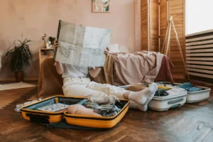 Person packing suitcases with a map in a cozy bedroom, preparing for a journey at Big Sur Cliff-side