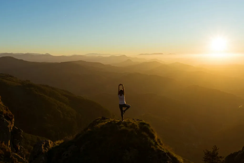 woman stretching on mountain top during sunrise from US Yoga Vacation
