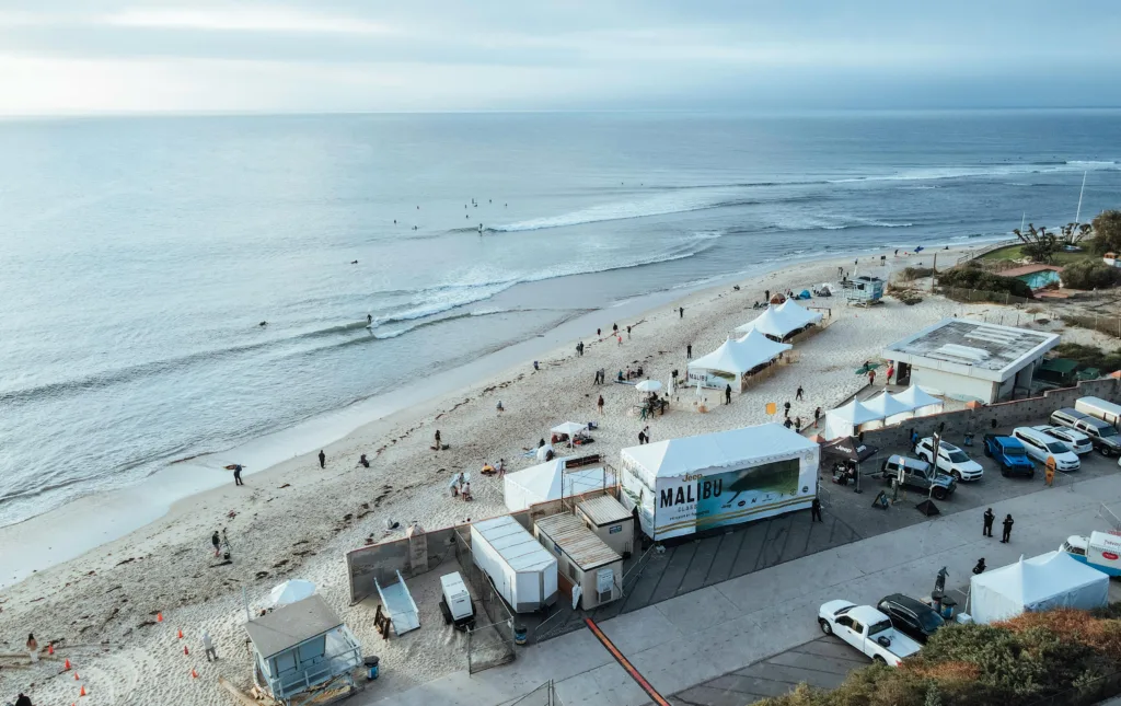 Aerial shot of a beach in Malibu featuring tents and people enjoying the coastal scenery from 7 Hidden Costs of Malibu Silent Weekends