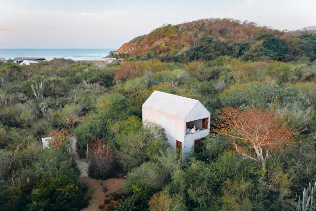 A serene modern house surrounded by dense foliage with ocean view, captured from above from California Retreats