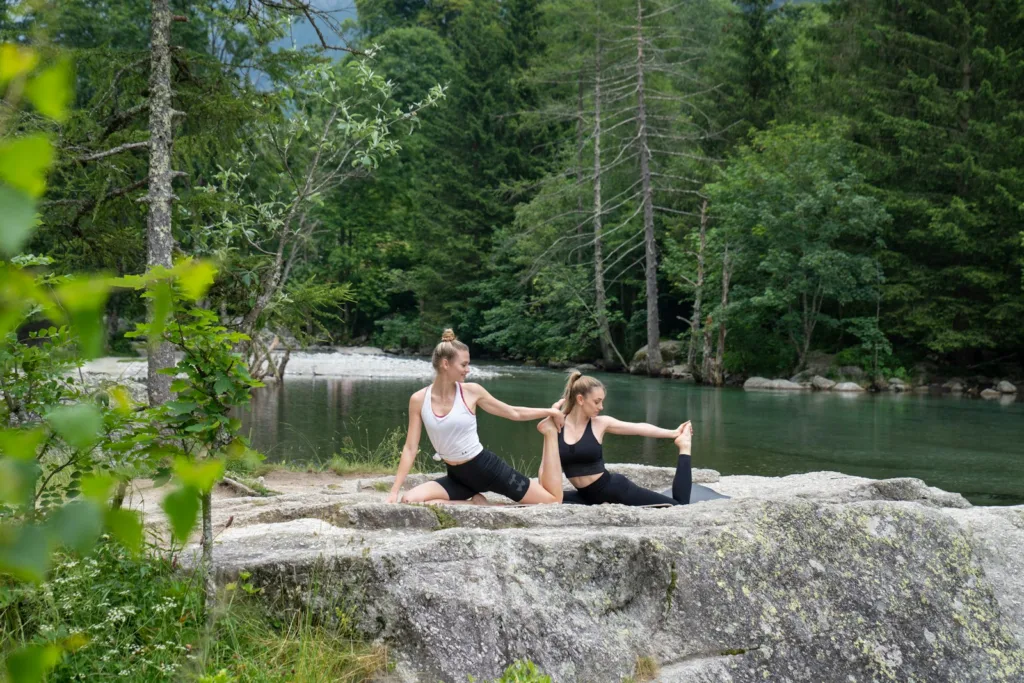 two women doing yoga on a rock near a river from US Yoga Vacation